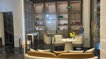 A modern hotel lobby with a seating area, a reception desk, and a display of amenities.