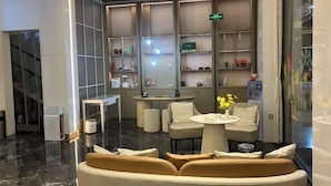 Ένας σύγχρονος χώρος υποδοχής με έναν καναπέ, ένα στρογγυλό τραπέζι και μια μικρή περιοχή με μπαρ.