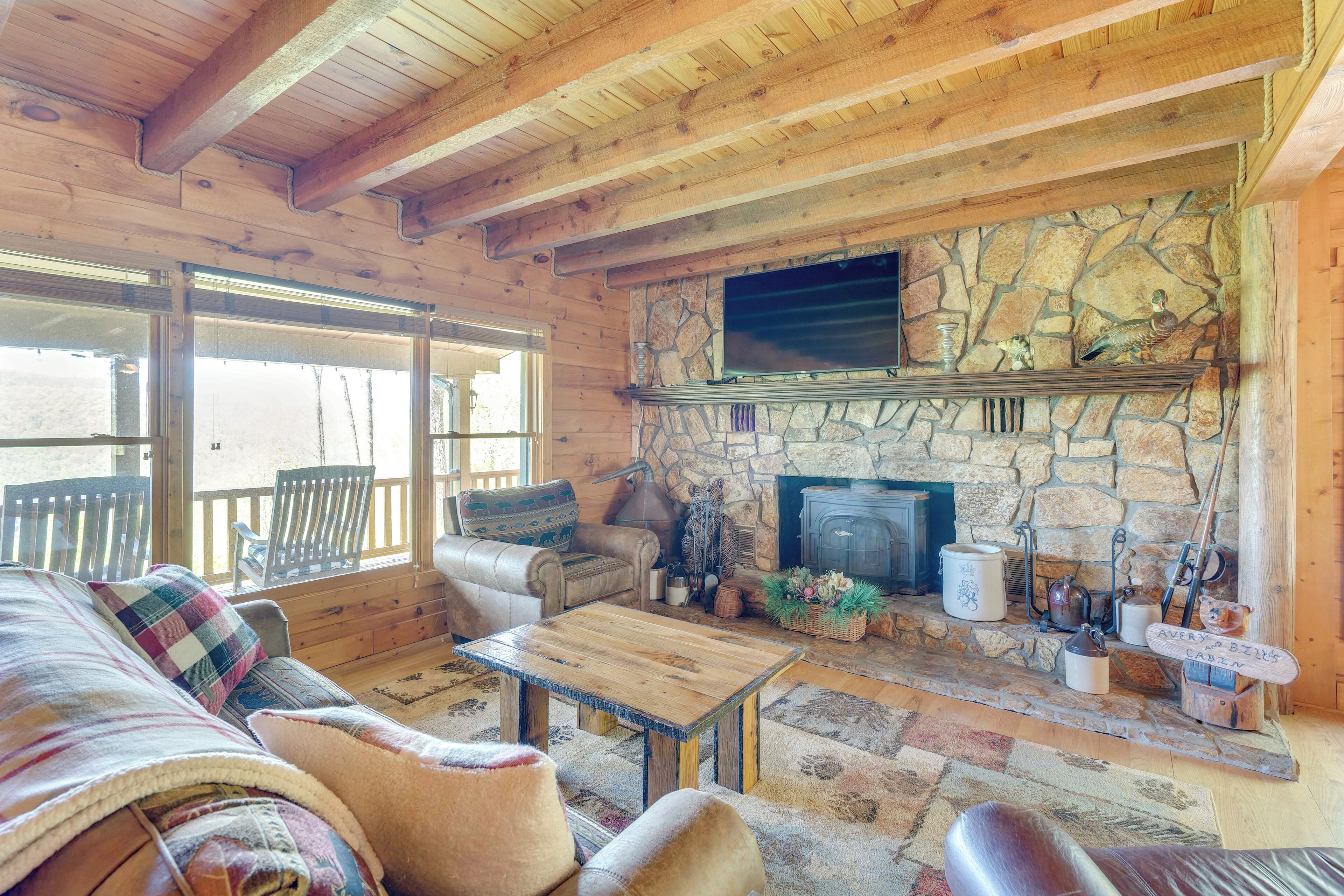 Interior acollidor d'una cabana amb una llar de pedra, mobles de fusta i un televisor penjat a la paret.