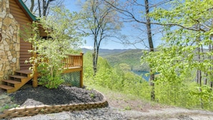 Une cabane en rondins dotée d’une terrasse en bois et d’un escalier en pierre menant à un porche.