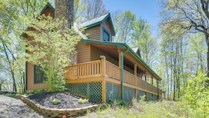 Une cabane avec une façade en bois, une cheminée en pierre et une véranda dotée de balustrades en treillis.