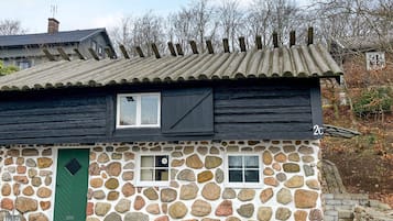 A stone house with a green door, two windows, and a number '2C' sign.