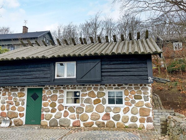 A stone house with a green door, two windows, and a number '2C' sign.