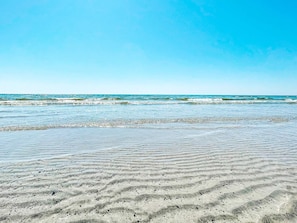 Ein Strand mit blauem Himmel und sanften Wellen.