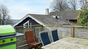 An outdoor patio with a wooden table and chairs, a green grill, and a wooden fence. - 4 Star Holiday Home in Bastad (Bastad)