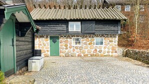 A rustic stone house with a green door, a small window, and a cobblestone driveway. - 4 Star Holiday Home in Bastad (Bastad)