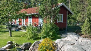 A red wooden house with a red roof, surrounded by greenery and rocks. - 4 Person Holiday Home in Graso (Gräsö)