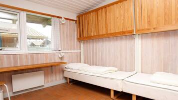 Ein kleiner, gemütlicher Raum mit einem hölzernen Etagenbett, einem Tisch und einem fenster mit Vorhängen.