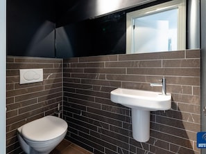 A bathroom with a toilet, a sink, and a window. - Elegant Seaside Apartment (De Haan)