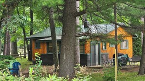 Une cabane avec un toit végétalisé, des murs en bois et une véranda avec des chaises.