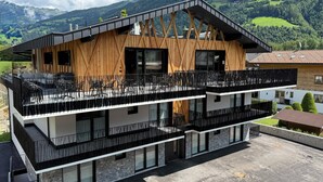 A modern multi-story building with balconies, large windows, and a view of a mountainous landscape. - Chalet in Zillertal Near Ski Slopes & Whirlpool (Aschau Im Zillertal)
