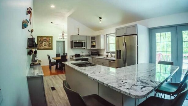 A modern kitchen with a marble countertop, stainless steel appliances, and a dining area with chairs. - Spring Discounted Rates!  
Spacious w/hot tub/grill/firepit 4 BR Red River Gorge (Rogers)