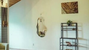 A spacious room with wooden flooring, a wooden ceiling, a bench, a mirror, a painting, and a black shelving unit with a plant. - Spring Discounted Rates!  
Spacious w/hot tub/grill/firepit 4 BR Red River Gorge (Rogers)