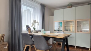A modern dining area with a wooden table, grey upholstered chairs, and a light grey cabinet with glass doors. - Kurzurlaub in Bockswiese, Hahnenklee (Goslar)