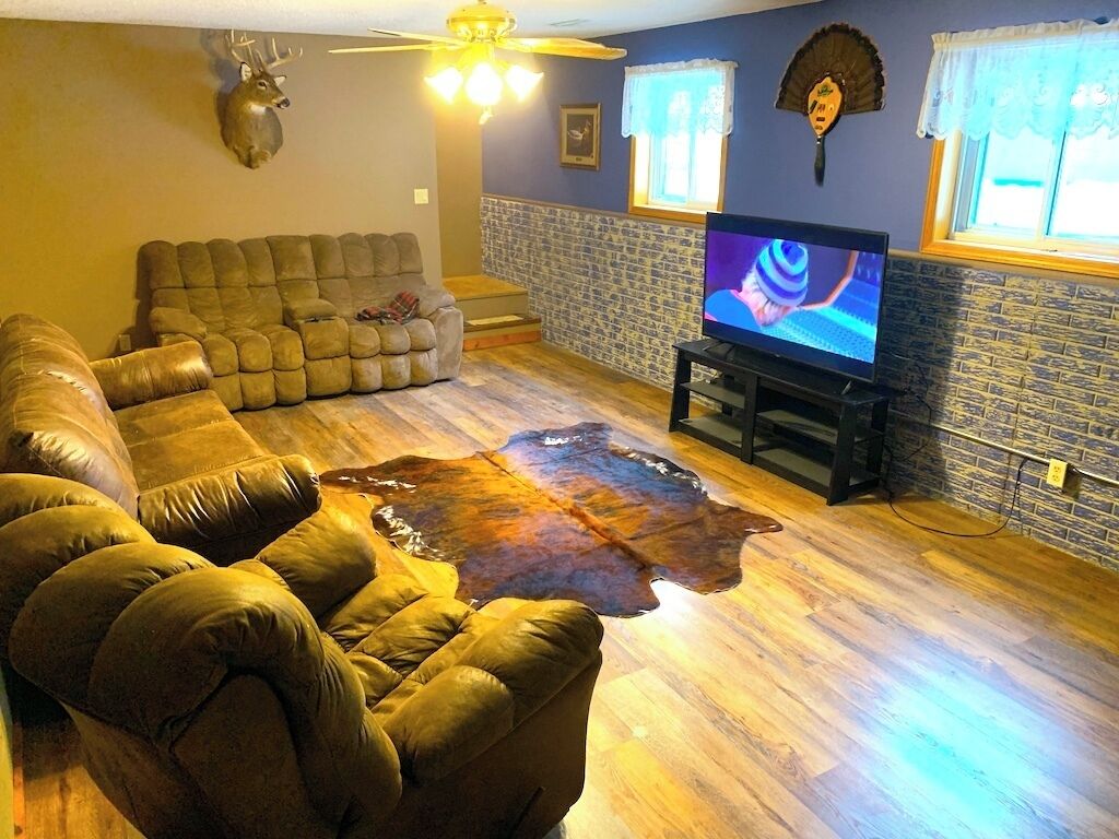 A living room with a sectional sofa, a television, and a stone accent wall.
