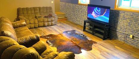 A living room with a sectional sofa, a television, and a stone accent wall.