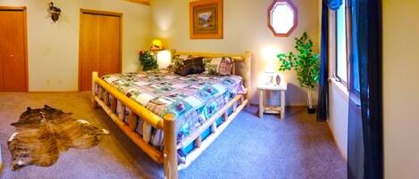A bedroom with a wooden bed, a small bedside table, a lamp, a potted plant, and a rug.