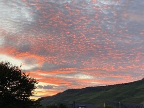 A sunset over a hilly landscape with a clear sky and scattered clouds.