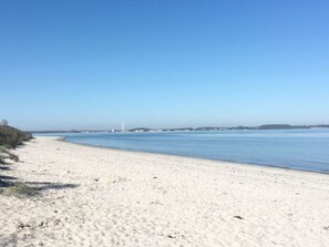 Une plage de sable fin, sous un ciel bleu clair et avec une eau calme.