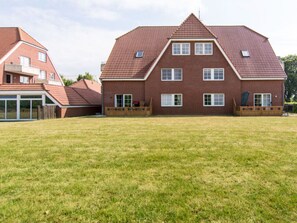 Une grande maison en briques, dotée d’un toit en pente, de nombreuses fenêtres et d’une vaste pelouse.