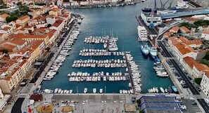 A marina with boats docked in rows, surrounded by buildings with red roofs.