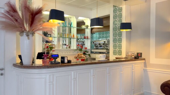 A bar area with a white counter, glass shelves with bottles, and a large mirror. - Bajamar Beach Hotel (Formia)