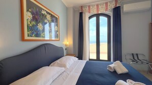 Una habitación de hotel con una cama, un cuadro, una ventana con cortinas y una silla.