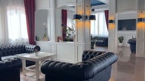 Una sala de estar moderna con sofás de cuero negro, una mesa de centro blanca y un televisor de pantalla plana grande montado en la pared.