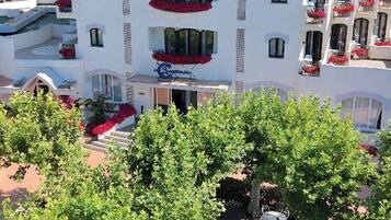 Un hotel con varios balcones, mobiliario exterior y un paisaje montañoso.
