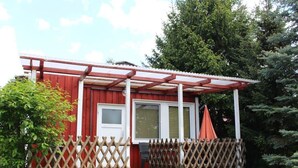 Eine kleine, rote Holzhütte mit einer Veranda und einem Holzzaun.