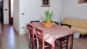 A dining area with a table set for four, a sofa, and a framed picture on the wall.