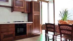 A kitchen with wooden cabinets, a stove, and an oven. There is a dining area with two chairs and a table.