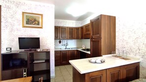 A compact kitchen with wooden cabinets, a built-in TV, and a small dining area. - Casa Marilda 2 - A 200 M dal Mare a Santa Maria Di Leuca (Castrignano del Capo)