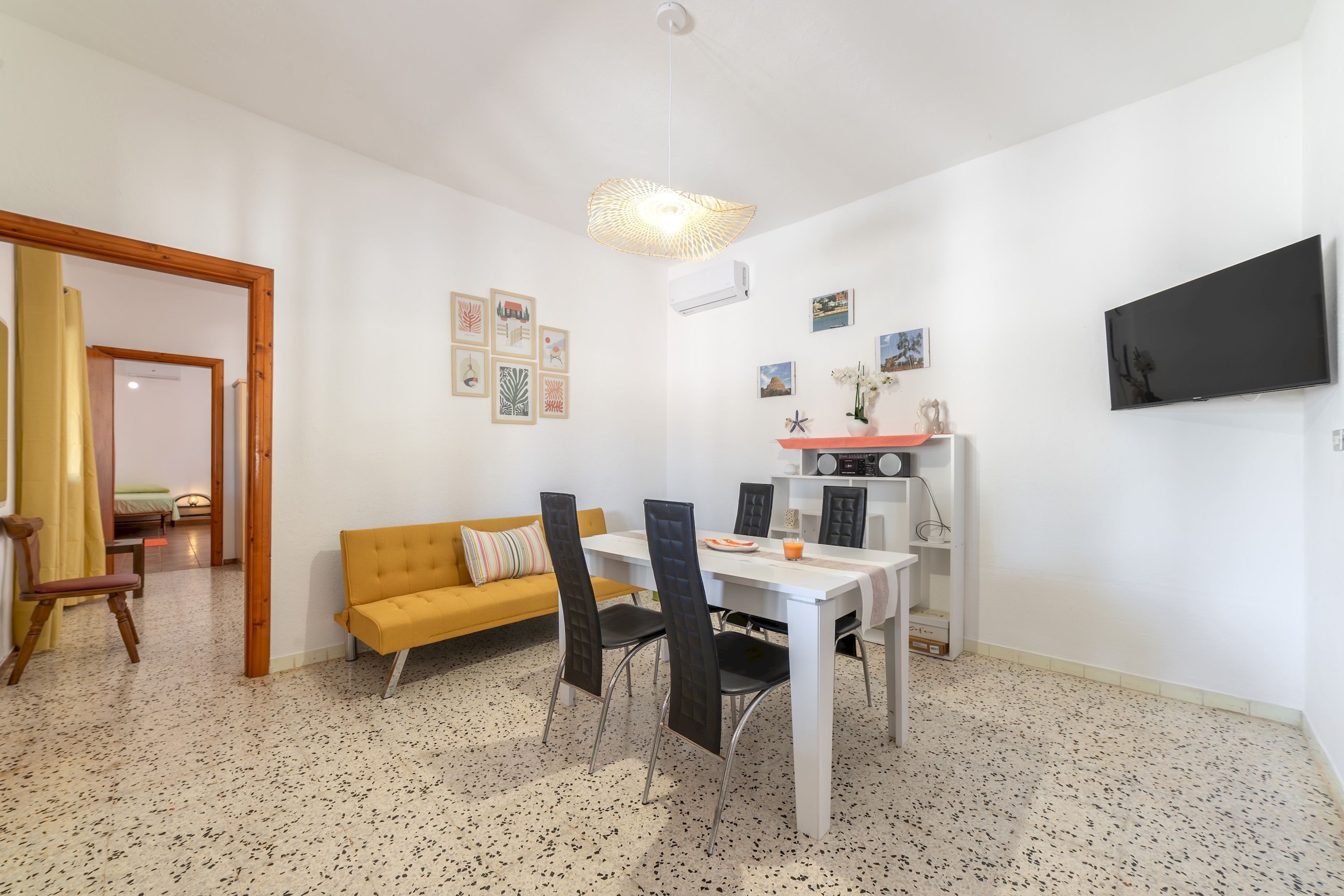 Ein gemütlicher Wohnbereich mit Essplatz, einer Couch, einem Fernseher und Wandbildern.