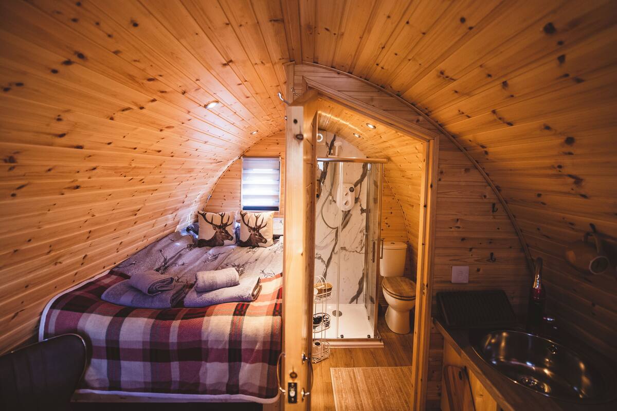 Un dormitorio acogedor en el ático, con cama, baño y una pequeña kitchenette.