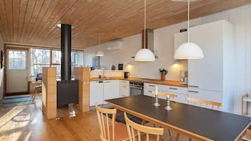 Una cocina moderna con pisos de madera, una isla central, luces colgantes y una estufa empotrada.
