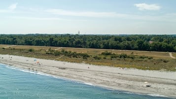 Una playa con agua cristalina, una orilla arenosa y un área boscosa al fondo.