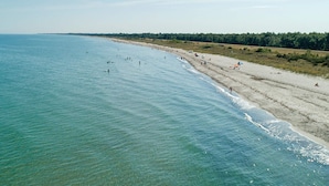 Una playa con agua cristalina, una orilla arenosa y una zona boscosa al fondo.