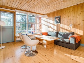 L’intérieur chaleureux d’un chalet avec un plafond en bois, un canapé, une table à manger et une chaise.
