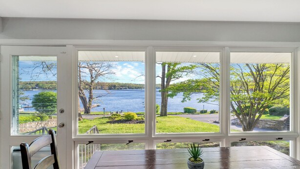 A dining area with a view of a lake and trees through large windows. - Stunning Lakeside Retreat (Columbia)