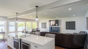A modern kitchen with a central island, built-in ovens, and a dining area with a dark leather couch. - Stunning Lakeside Retreat (Columbia)