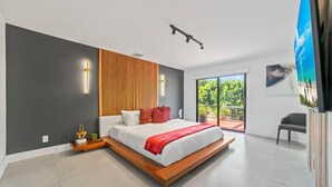 Une chambre moderne avec un grand lit, une tête de lit en bois et une vue sur la verdure.