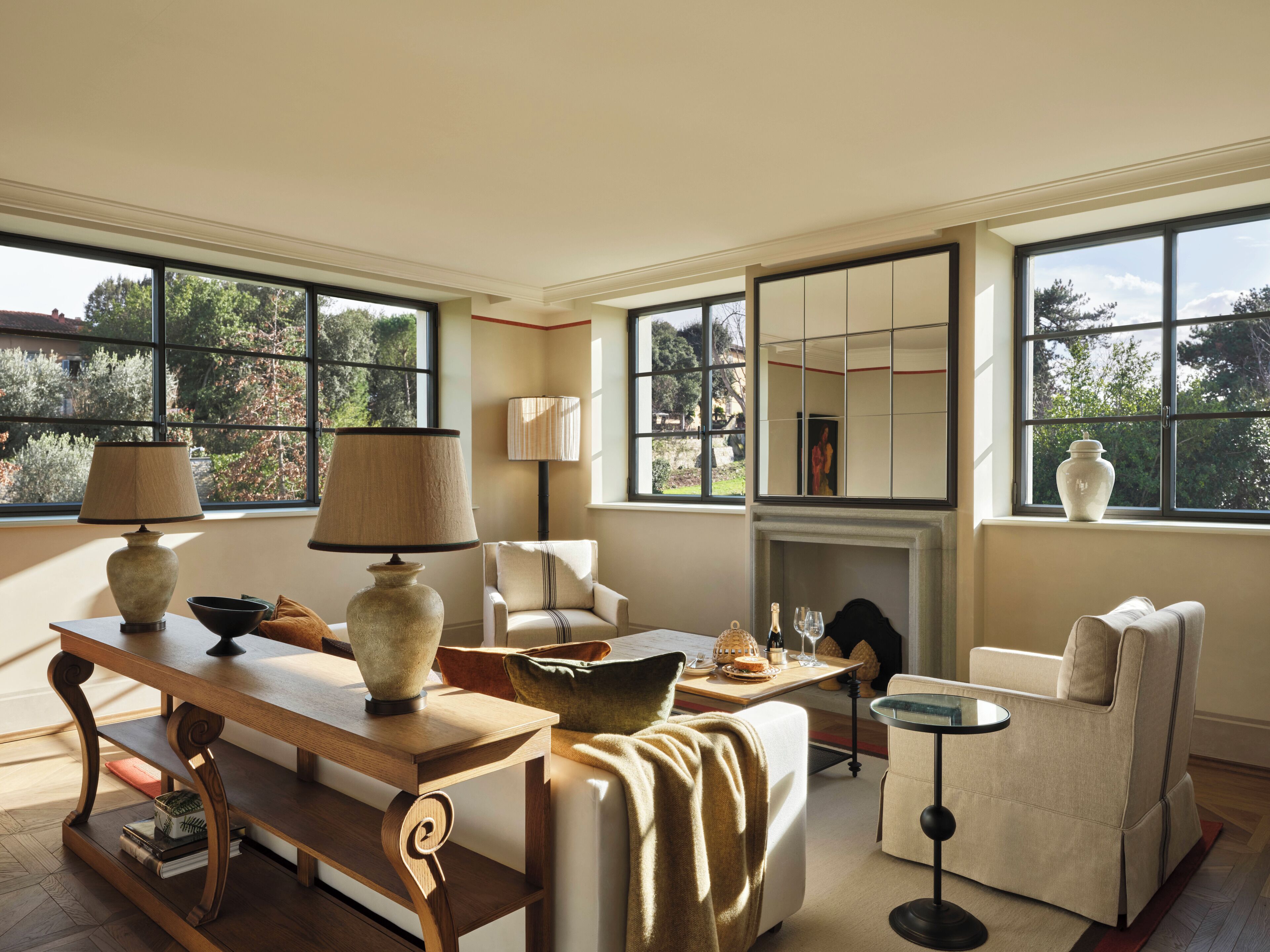 A spacious living room with a wooden table, two lamps, a sofa, and a fireplace.