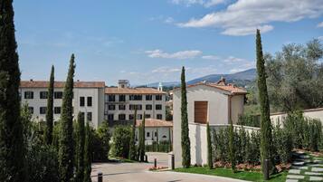 A multi-story building with a courtyard, surrounded by tall cypress trees and a well-maintained lawn.