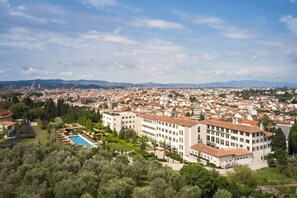 Um hotel com vários andares, piscina e vista para o horizonte urbano.