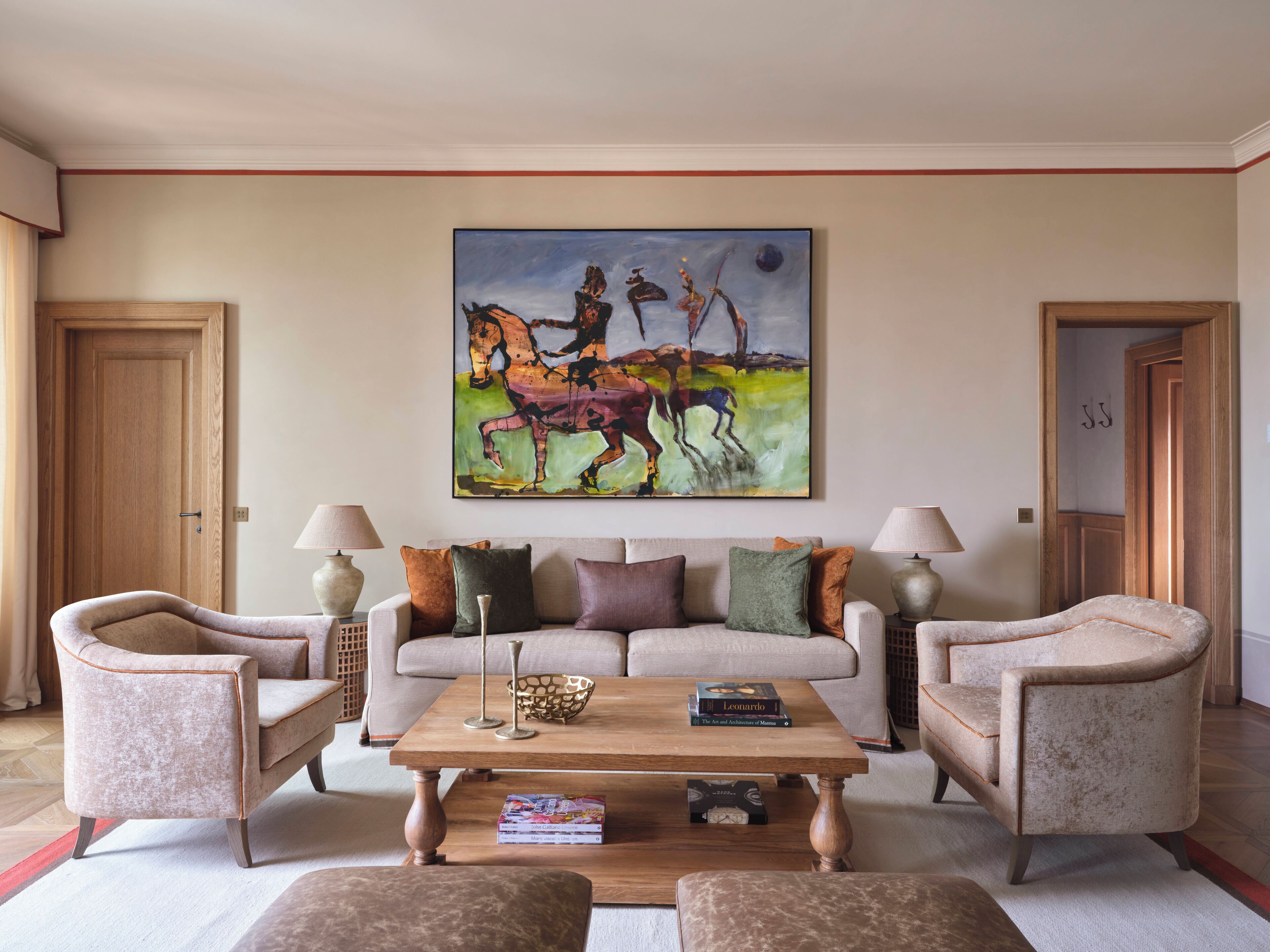 Un salon avec un canapé, deux fauteuils, une table basse et un tableau accroché au mur.