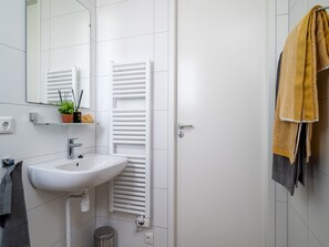 A modern bathroom with a white sink, mirror, and towel rack.
