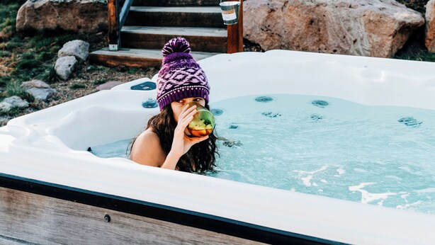 A hot tub with a person in it, surrounded by rocks and trees. - Sunflower Cabin- Mountain Views- Hot tub (Florissant)