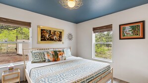 A bedroom with a bed, a window, and a painting on the wall. - Sunflower Cabin- Mountain Views- Hot tub (Florissant)