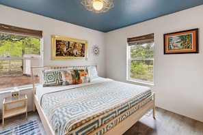 Un dormitorio con cama, ventana y un cuadro en la pared.